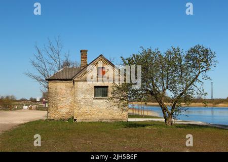 Petit et ancien cottage en briques avec une cheminée près d'un canal. Endroit idyllique pour vivre près de la rivière. Banque D'Images