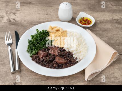 Féijoada brésilienne typique avec riz, poivre, farofa, chou frisé et crépitements. Banque D'Images