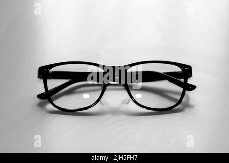 Flou artistique des lunettes noires sur fond blanc. Flat lay, vue de dessus. Une paire de lunettes à rebord foncé vues de l'avant, avec les temples ouverts. Le dos Banque D'Images