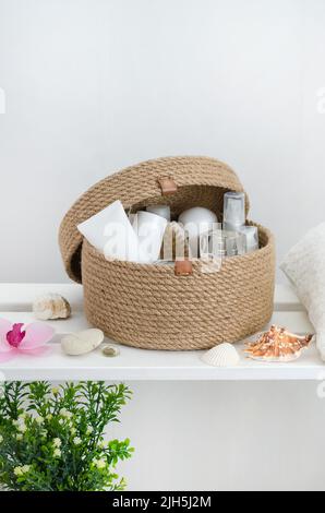 Panier en jute tricoté à la main avec couvercle avec accessoires et cosmétiques dans la salle de bains sur un rack en bois blanc avec espace pour les copies. Banque D'Images