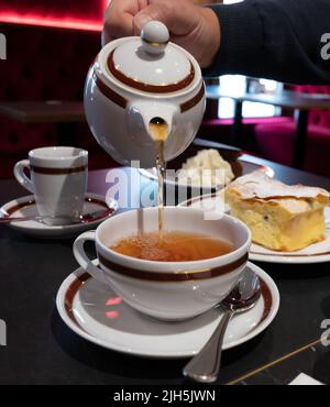 Temps du thé en Angleterre, verser du thé noir earl Grey avec bergamote dans une tasse, thé dînatoire servi café à Londres, gros plan Banque D'Images