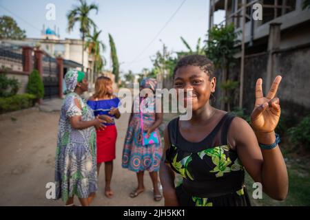 Gros plan d'une jeune fille africaine souriante faisant le V signe avec ses doigts, derrière 3 autres femmes africaines, groupe de femmes d'âges différents ensemble Banque D'Images