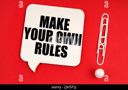 Concept d'entreprise. Sur fond rouge, les trombones sont un point d'exclamation et une plaque de réflexion avec l'inscription - faites vos propres règles Banque D'Images
