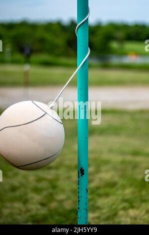 Tetherball assis libre à côté du poteau dans une arrière-cour. Banque D'Images