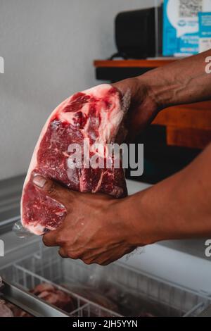 Fine découpe de viande dans les mains d'une boucherie en la sortant du congélateur. Photo de haute qualité. Viande crue. Excellente coupe de viande fraîche. Viande rouge. Banque D'Images