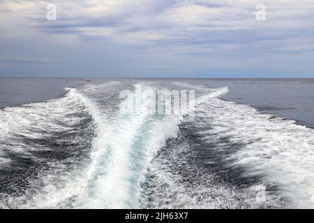 Un moteur hors-bord se réveille d'un bateau de croisière sur la mer dans un paysage marin avec l'horizon au-dessus de l'eau lors d'une journée nuageux à l'île de Langara située à Hai Banque D'Images
