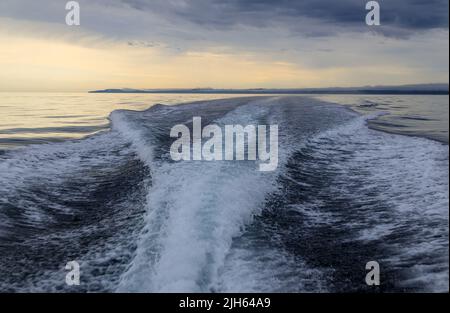 Un moteur hors-bord se réveille d'un bateau de croisière sur la mer dans un paysage marin avec l'horizon au-dessus de l'eau lors d'une journée nuageux à l'île de Langara située à Hai Banque D'Images