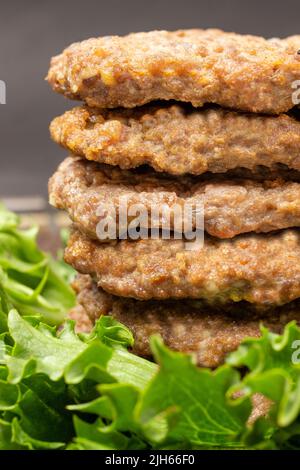 Hamburgers frits en pile avec salade verte. Gros plan. Arrière-plan noir Banque D'Images