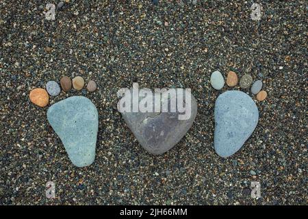 Marches de l'homme, de la femme et du coeur en pierres sur la plage de sable. Banque D'Images