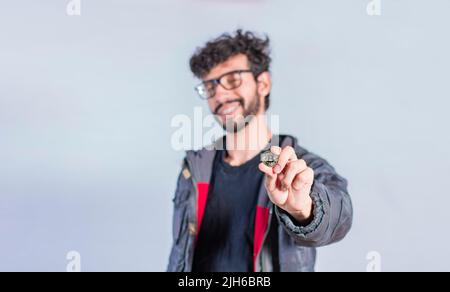 Homme souriant tenant une pièce de monnaie en bitcoin, homme beau montrant une pièce de monnaie en bitcoin, personne tenant une pièce de monnaie en bitcoin isolée Banque D'Images