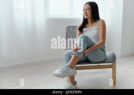 Crampes orteil cassé os cassé dans la jambe. Souffrance tourmentée bronzée belle jeune femme asiatique touche la jambe à la maison intérieur salon. Blessures faibles Banque D'Images