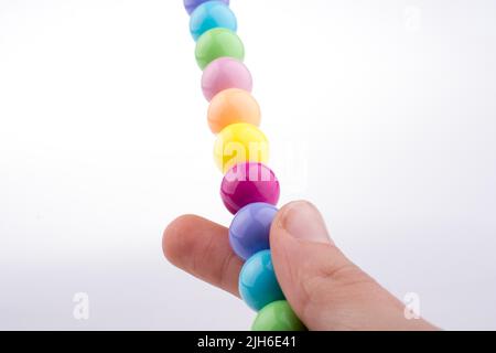 Tenir la main perles de couleur avec l'expression du visage sur fond blanc Banque D'Images