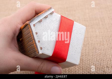 Petit modèle chambre enveloppée d'un ruban rouge sur une toile Banque D'Images