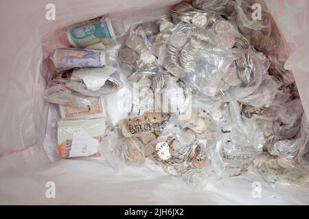 Des billets de banque et des pièces de monnaie au fond d'un sac Banque D'Images