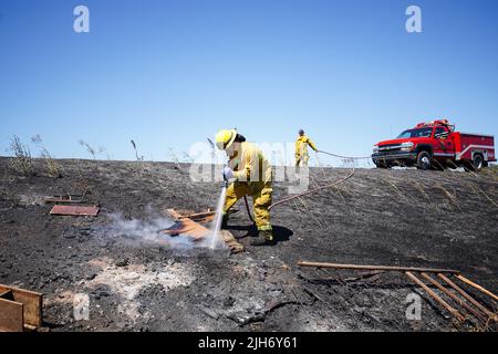 Richmond, États-Unis. 15th juillet 2022. Un pompier utilise de l'eau pour éteindre le feu de broussailles à Richmond. Les pompiers répondent à un incendie de brosse à Richmond, le feu de brosse a commencé vers 1 h 22 et a été contenu par 2 h. la cause de l'incendie est la combustion ouverte de déchets dans la région. Crédit : SOPA Images Limited/Alamy Live News Banque D'Images