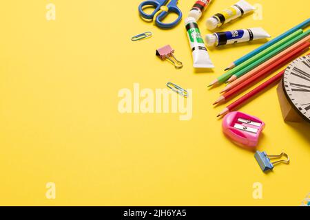 Imaginez différents articles de bureau et ustensiles en plastique, peintures, crayons sur fond jaune Banque D'Images