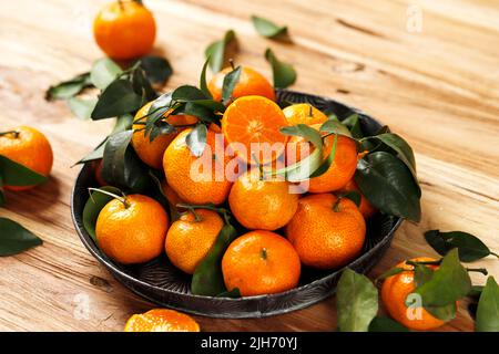 Fruits frais de la petite mandarine aux oranges ou Tangerines avec des feuilles sur un plateau rustique sur une table en bois Banque D'Images