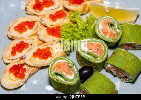 Quelques sushis verts au poisson rouge et crêpes au caviar rouge en gros plan Banque D'Images
