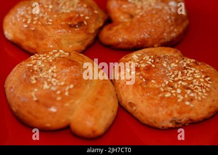 Cuisine orientale arabique égyptienne de petits gâteaux arrondis couverts de sésame et de sucre, desserts de fête Eid El Fitr et bonbons du Ramadan sur un plat rouge en céramique Banque D'Images