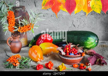 L'automne encore la vie avec l'argousier dans une carafe, des légumes, des baies et des feuilles colorées sur un fond gris rugueux. Mise au point sélective Banque D'Images