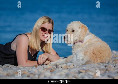 Femme jouant avec un chien sur la plage Banque D'Images