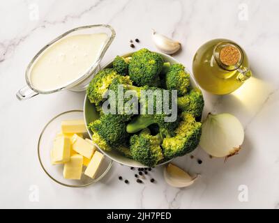 Ingrédients crus pour la cuisson de la crème de brocoli : bouquets de brocoli, crème, beurre, ail, oignon et huile d'olive. Recette de soupe de brocoli. Banque D'Images