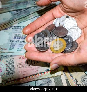 Rares pièces de roupie de la vieille banque indienne tombant sur des billets de monnaie, tombant sur une pièce de roupie indienne sur une centaine de billets de roupies, pièces de monnaie indienne tombant Banque D'Images