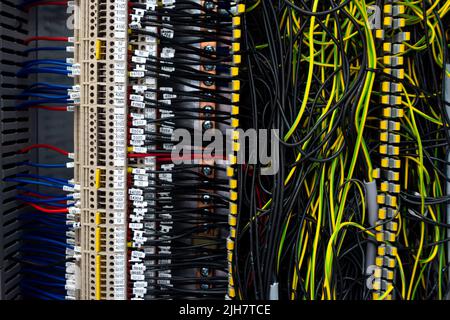 Faisceaux électriques connectés aux bornes de l'armoire de commande d'une machine industrielle. Extrémités de câble signalées par des descriptions Banque D'Images