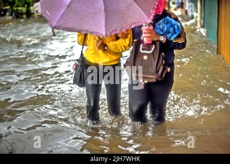 Des femmes marchant sur une passerelle inondée à Jakarta, après une pluie continue ont quitté le centre-ville de la capitale indonésienne inondé. Banque D'Images