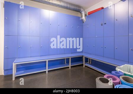 Casiers en bois bleu avec banquettes assorties dans le vestiaire de la salle de sport Banque D'Images