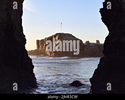 Chapelle Rock sur la plage de Perranporth au coucher du soleil depuis l'entrée de la grotte Banque D'Images