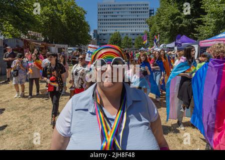 Southend on Sea, Royaume-Uni. 16 juillet 2022. Une scène vibrante d'un défilé UK Pride montrant un participant souriant portant des lunettes de soleil, un bandeau et des cordons sur le thème de l'arc-en-ciel. L’arrière-plan présente d’autres participants, des drapeaux de fierté, des tentes et une ligne d’horizon urbaine, capturant l’esprit d’inclusion, de célébration et de solidarité LGBTQ+. Les 1000 participants se réunissent pour l'événement Southend Pride, avant que le défilé ne commence le long de High Street et dans les jardins de Warrior Square pour un festival de la fierté avec des spectacles d'animation. Penelope Barritt/Alamy Live News Banque D'Images
