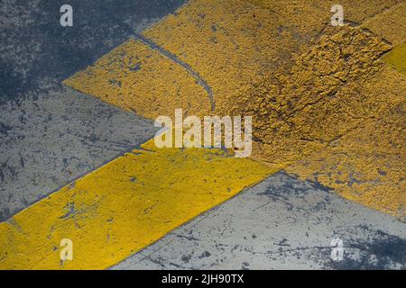 Bandes réfléchissantes jaunes peintes sur une chaussée de stationnement, texture de grunge de route, détails abstraits Banque D'Images