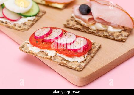 Différents pains à croûtes au jambon, à la tomate, au radis, au concombre et au fromage. Petit déjeuner facile. Alimentation. Sandwichs rapides et sains. Croustillant et garniture savoureuse. En-cas diététiques Banque D'Images