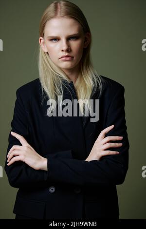 Le concept du mouvement des femmes. Une jeune fille forte et sûre d'elle-même, sérieuse et réussie, croise les bras sur sa poitrine et regarde dans la caméra qui pose Banque D'Images