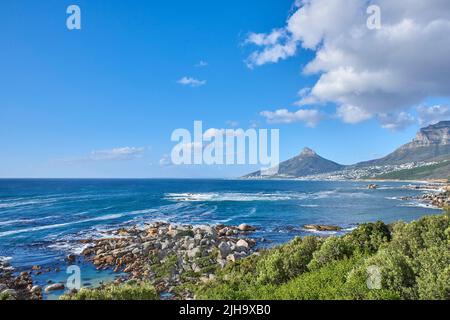 Un paysage naturel d'une mer calme et de buissons verts, avec la montagne de Lions Head à l'horizon, le Cap, Afrique du Sud. Paysage de l'océan près de Banque D'Images