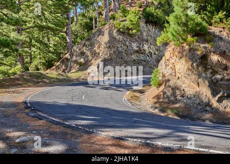 Route ou rue en courbe le long d'une vallée de montagne escarpée. Chemin sinueux avec courbe vive allant en haut de la colline avec des arbres des deux côtés du sentier sur un Banque D'Images