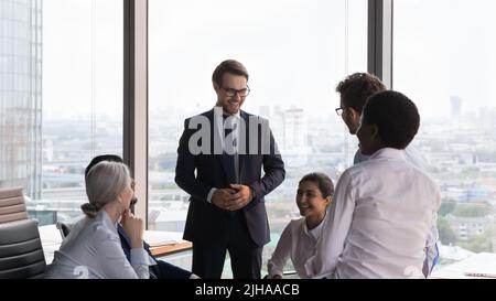 Un bon patron qui tient une réunion avec une équipe multiethnique et qui parle aux employés Banque D'Images