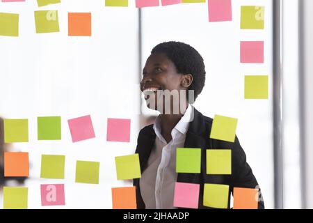 Femme d'affaires africaine joyeuse et réussie qui fait le calendrier du projet Banque D'Images