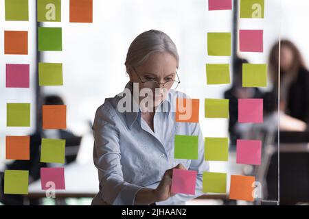 Une femme d'affaires senior et concentrée dans l'atelier de préparation des lunettes Banque D'Images