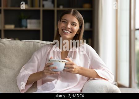 Femme reposant sur tient tasse de thé sourire regarder l'appareil photo Banque D'Images