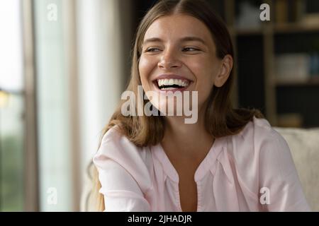 Riant jolie femme regardant de côté assis sur le canapé Banque D'Images