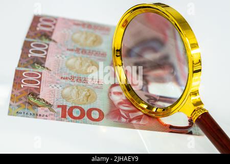 New Zealand Money, Flat lay, 100 dollars de factures, loupe, fond blanc, concept commercial et financier, observation du marché et de l'inflation, c Banque D'Images