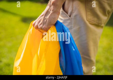 Un homme porte un drapeau ukrainien entre ses mains. Concept patriote ukrainien, rassemblement en faveur de l'Ukraine Banque D'Images