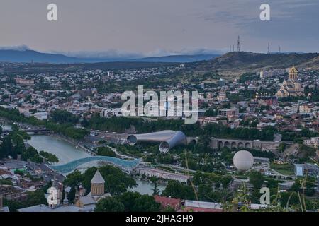 Tbilissi, Géorgie coucher de soleil vue panoramique depuis le sommet de la forteresse de Narikala montrant le pont de la paix, le parc Rike, la rivière Kura et la cathédrale Sainte-Trinité Banque D'Images