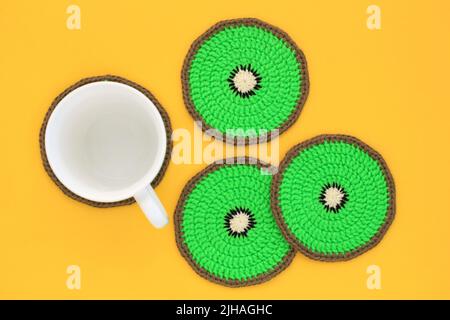 Kiwi fruit colurée crochet dessous de verre et whie tasse sur fond jaune. Décoration maison. Accessoires faits main à la main sur une table. Concept lumineux d'été Banque D'Images