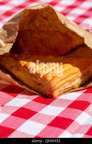 Transfert de pommes dans un sac de papier brun à l'extérieur sur un chiffon Vichy. Emballage de recyclage écologique Banque D'Images