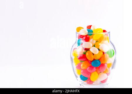 Jelly beans colorés dans un petit pot isolé sur un fond blanc Banque D'Images