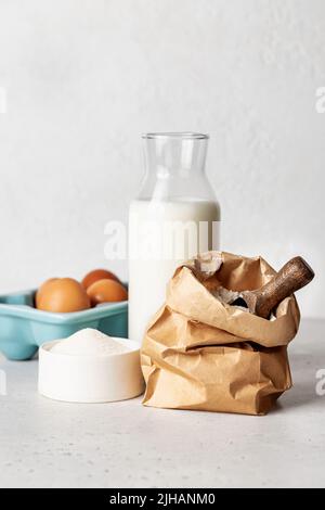 Produits de boulangerie - farine, œufs, lait, sucre sur fond blanc. Mise au point sélective. Orientation verticale Banque D'Images