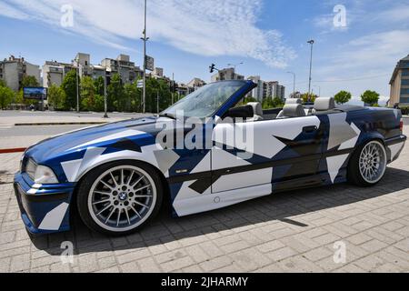 Vue de la voiture de sport BMW 3 E36 cabriolet avec jantes de sport et couvert de décalcomanies garées dans la rue. Banque D'Images